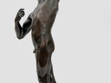 statue en bronze représentant un homme tenant un arc et une flèche, posée sur un socle en bois