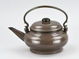 a brown teapot with a handle on a white surface