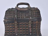 a small wicker basket with a handle on a white surface