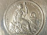 a silver coin with a woman sitting on top of it