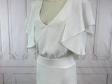 the dress is white and has ruffles on the shoulders