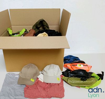 une boîte en carton remplie de vêtements et de chapeaux, posée par terre