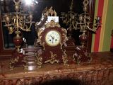une horloge posée sur une cheminée, à côté d'un miroir