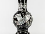 un vase noir orné d'un motif sur fond blanc