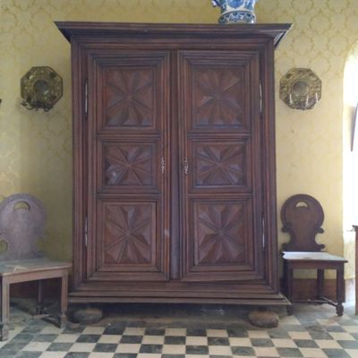 une grande armoire en bois dans une pièce au sol en damier