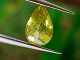 un gros plan d'un diamant jaune tenu par une pince