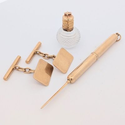 une photo représentant un stylo, des boutons de manchette et un flacon de parfum posés sur une table