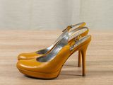 yellow high heeled shoes on a wooden table against a gray wall