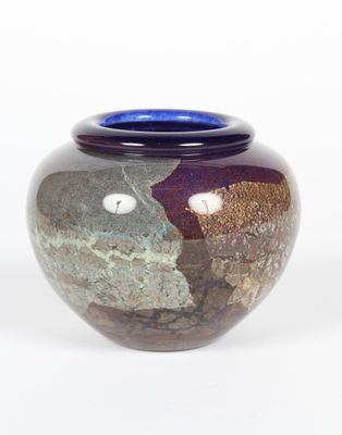 un vase avec un couvercle bleu posé sur une surface blanche