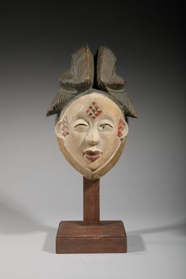 un gros plan d'une sculpture représentant un visage, posée sur un socle en bois