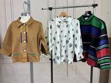 three shirts hanging on a clothes rack in a room