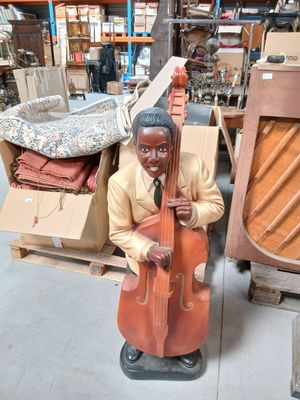 une statue représentant un homme tenant un violoncelle dans un magasin