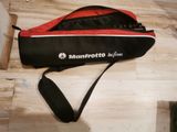 a red and black bag on the floor with a black strap