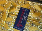 a label on a yellow and blue tie with a red and white design