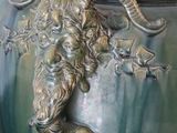 a green vase with a ram head on it on a table