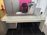 a glass desk with a computer on it in a room