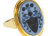 une image représentant une bague dorée et bleue ornée d'un blason