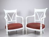 une paire de fauteuils peints en blanc avec des coussins rembourrés rouges