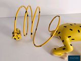 a yellow sculpture of a cheetah laying on the ground