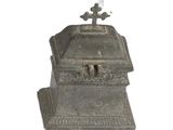 une petite boîte en métal surmontée d'une croix