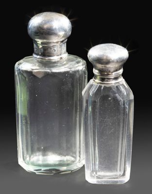 two clear glass bottles with silver lids on a black surface