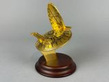 gold plated bird on a wooden base on a grey background