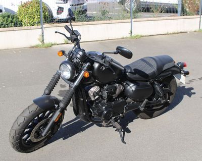 a black motorcycle parked in a parking lot next to a fence