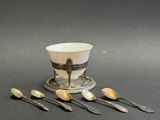 five spoons and a cup sitting on a table