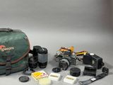 un appareil photo, un étui pour appareil photo, un objectif, un étui pour appareil photo et d'autres objets disposés sur une table