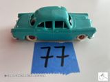 une petite voiture verte posée sur une feuille de papier bleue