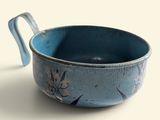 a blue bowl with a handle sitting on a table