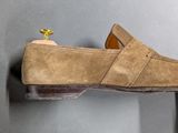 someone is holding a pair of brown shoes on a wall