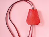 red leather handbag with two silver rings on a pink background