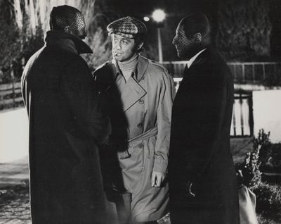 photographie en noir et blanc de trois hommes en imperméables, debout les uns à côté des autres