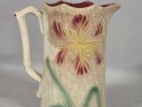 a small pitcher with a flower painted on it