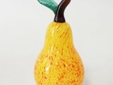 a small yellow and red ceramic pear on a white surface