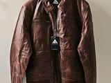 une veste en cuir marron suspendue à un cintre accroché au mur
