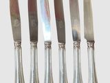 quatre couteaux sont alignés les uns à côté des autres sur une surface blanche