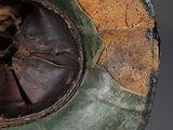 an old green and brown helmet with a hole in the middle