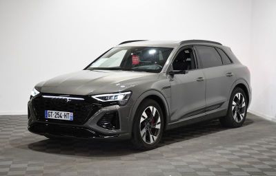 un SUV Audi gris garé dans une pièce au sol carrelé en damier