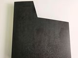 a close up of a piece of black paper on a white surface