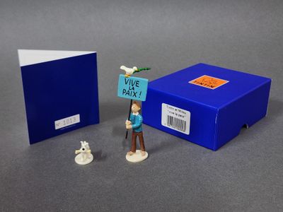 une petite figurine représentant un homme tenant une pancarte à côté d'une boîte