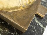 a bronze statue of a man holding a banana on a marble table