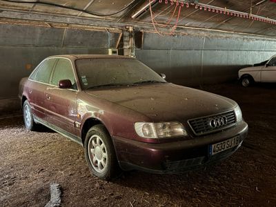 une voiture sale garée dans un garage, avec d'autres voitures en arrière-plan