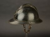 a silver helmet that is on a glass stand