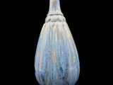 un vase bleu posé sur une surface noire