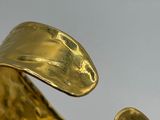 a close up of a gold bracelet on a white surface