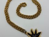 a gold chain with a black flower pendant on it