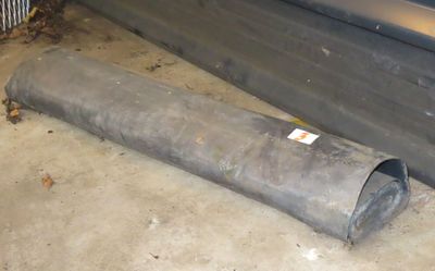 a pipe that is laying on the ground next to a car