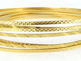 a close up of a stack of gold bracelets on a white surface